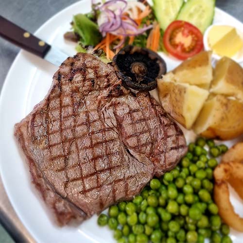 Grilled steak with salad, jacket potato and peas